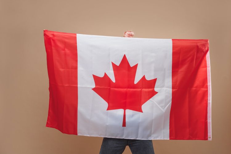 Beautiful blonde woman standing with Canadian flag