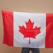 Beautiful blonde woman standing with Canadian flag